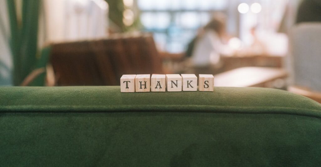 Como Praticar a Gratidão para Melhorar seu Bem-Estar Diário 2 Wooden blocks spelling 'Thanks' on a green surface in relaxed indoor setting.