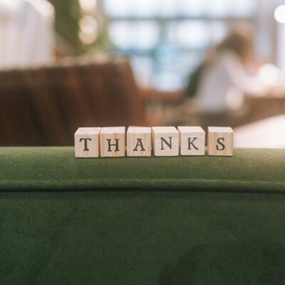 Wooden blocks spelling 'Thanks' on a green surface in relaxed indoor setting.