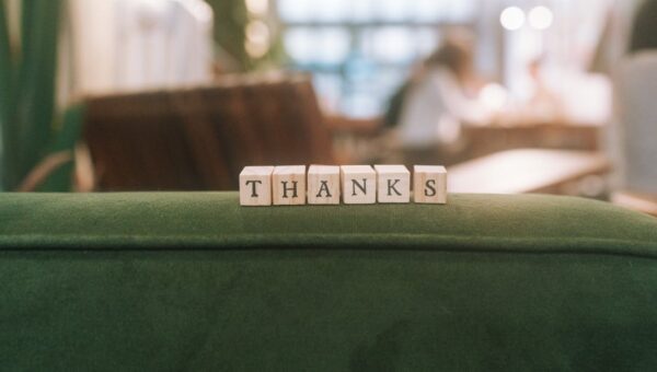 Wooden blocks spelling 'Thanks' on a green surface in relaxed indoor setting.