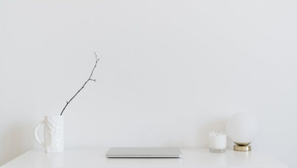 A clean, minimalistic workspace featuring a white desk, laptop, and decorative items, perfect for modern design inspiration.