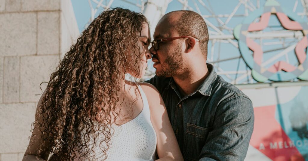 A romantic couple sharing a close moment outdoors in bright sunlight.