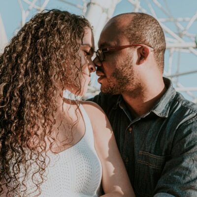 A romantic couple sharing a close moment outdoors in bright sunlight.