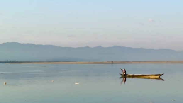A serene view of a fisherman in a boat on the calm Brahmaputra River near Biswanath Charali, Assam.