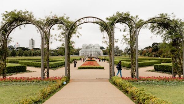 A scenic view of Curitiba's iconic botanical garden with lush greenery and elegant archway.