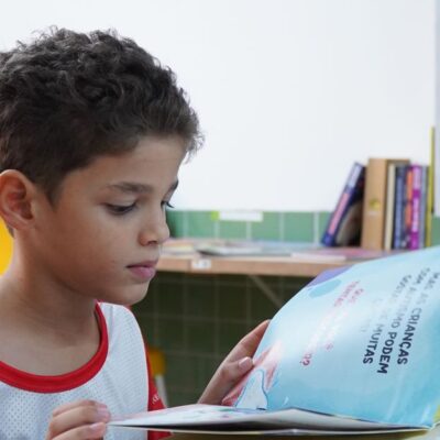 A young boy engrossed in reading a book in a classroom environment, promoting child literacy.