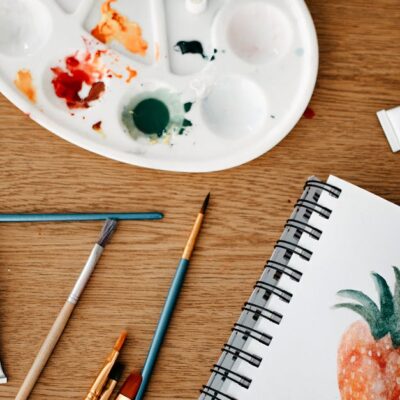 Explore a vibrant creative art space with watercolors and brushes on a wooden desk.