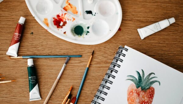 Explore a vibrant creative art space with watercolors and brushes on a wooden desk.