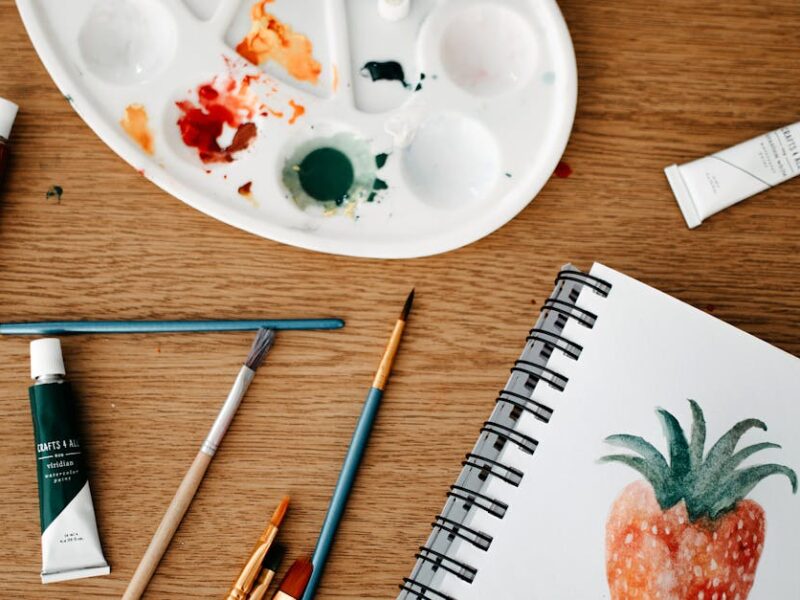 Explore a vibrant creative art space with watercolors and brushes on a wooden desk.