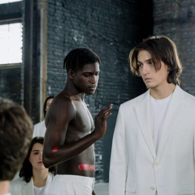 Models in a fashion shoot wearing white outfits in an industrial space.
