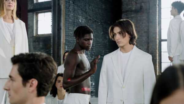 Models in a fashion shoot wearing white outfits in an industrial space.