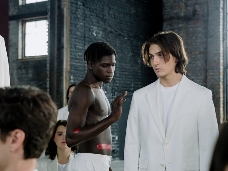 Models in a fashion shoot wearing white outfits in an industrial space.