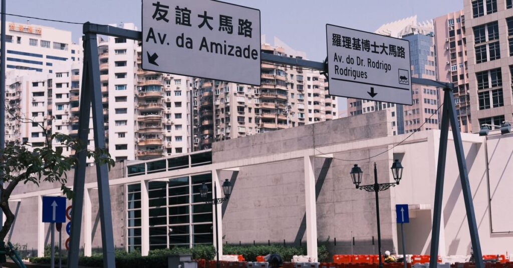 Street view in Macau with bilingual road signs and urban architecture.