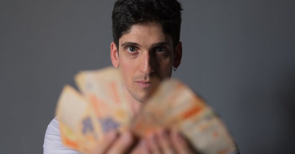 Focused portrait of a man holding Argentine Peso bills, emphasizing financial concepts.