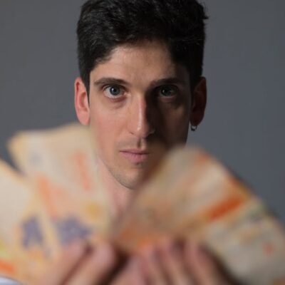 Focused portrait of a man holding Argentine Peso bills, emphasizing financial concepts.