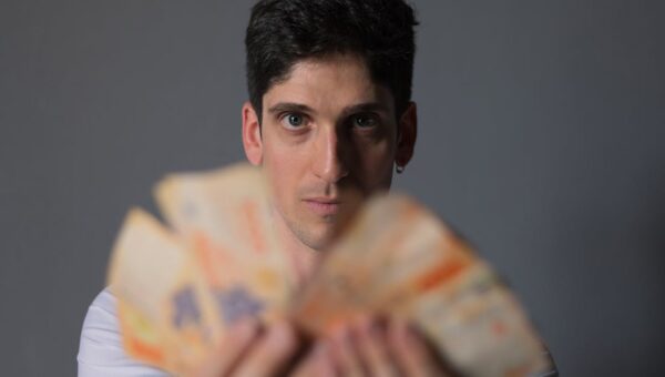Focused portrait of a man holding Argentine Peso bills, emphasizing financial concepts.