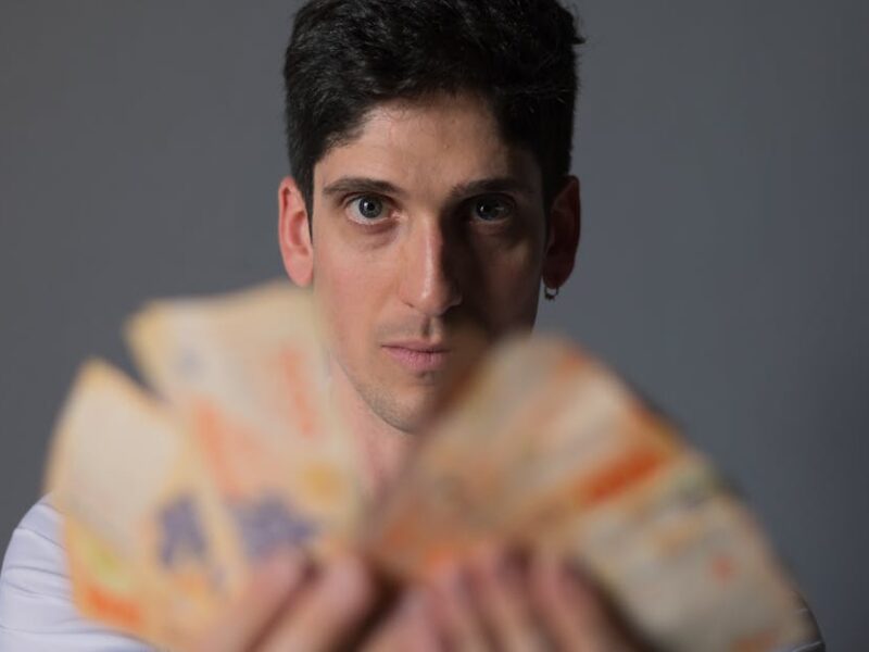 Focused portrait of a man holding Argentine Peso bills, emphasizing financial concepts.