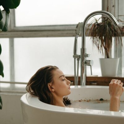 A woman peacefully soaking in a bathtub surrounded by plants and candles, embracing tranquility.