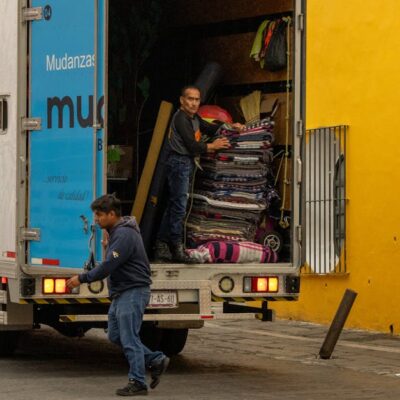 Workers loading a moving truck on a street in Mexico, urban lifestyle.
