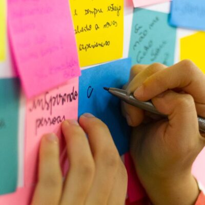 Hands writing on colorful sticky notes during a brainstorming session indoors.