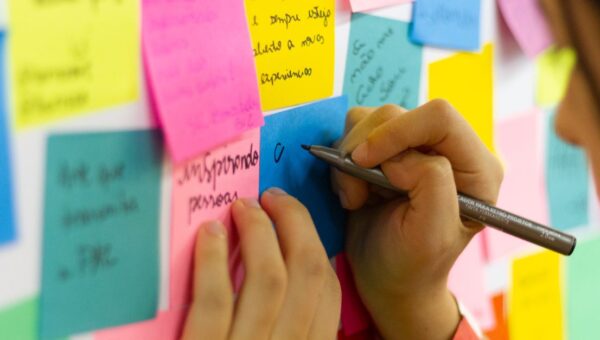 Hands writing on colorful sticky notes during a brainstorming session indoors.