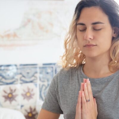 Peaceful woman meditating indoors, eyes closed, in a serene environment.