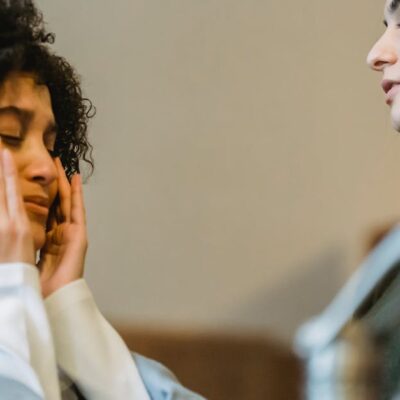Low angle side view of upset African American crying and wiping away tears near crop girlfriend