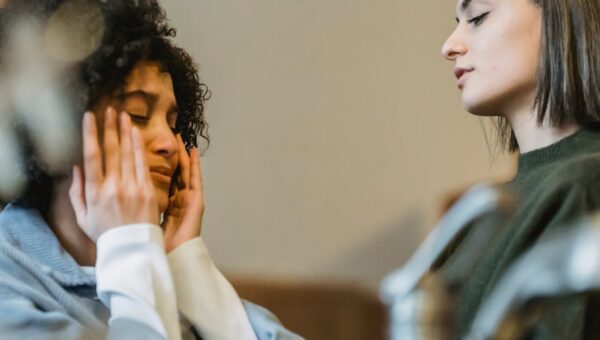 Low angle side view of upset African American crying and wiping away tears near crop girlfriend