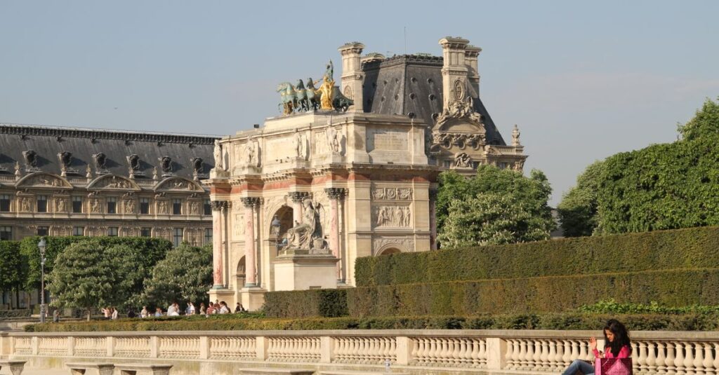 Sunny day at the Arc de Triomphe du Carrousel in Paris with people relaxing nearby.