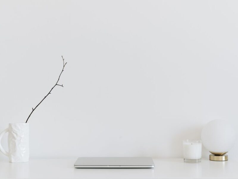 A clean, minimalistic workspace featuring a white desk, laptop, and decorative items, perfect for modern design inspiration.