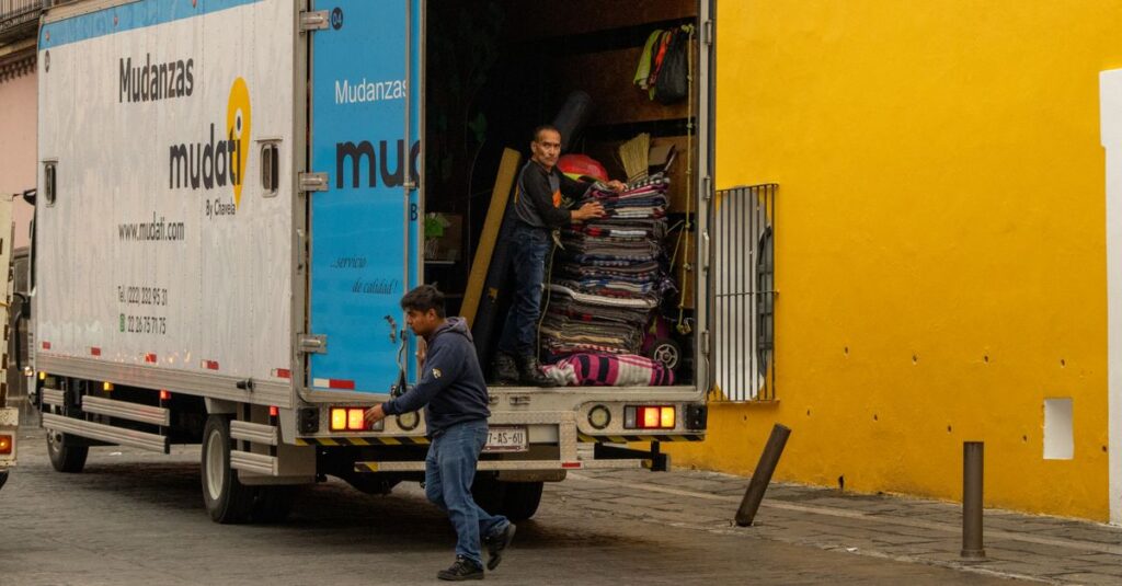 Como Lidar com o Medo de Mudanças e Encontrar Oportunidades 2 Workers loading a moving truck on a street in Mexico, urban lifestyle.