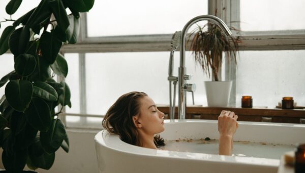 A woman peacefully soaking in a bathtub surrounded by plants and candles, embracing tranquility.