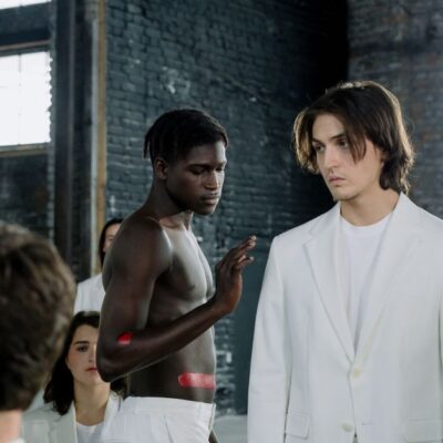 Models in a fashion shoot wearing white outfits in an industrial space.
