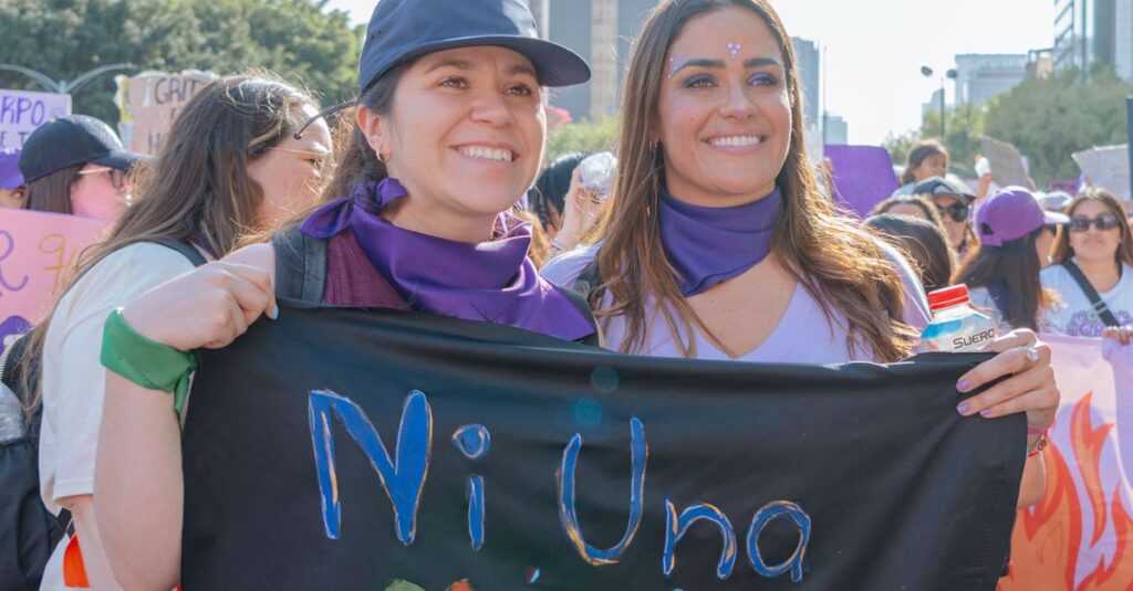 Mexican women participating in a city rally, holding a protest banner with 'Ni Una Menos' message.