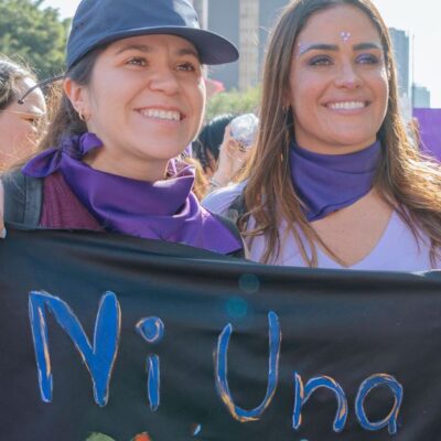 Mexican women participating in a city rally, holding a protest banner with 'Ni Una Menos' message.