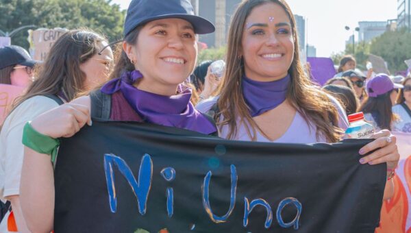 Mexican women participating in a city rally, holding a protest banner with 'Ni Una Menos' message.