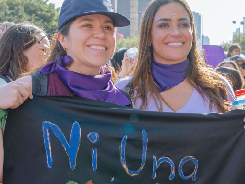 Mexican women participating in a city rally, holding a protest banner with 'Ni Una Menos' message.