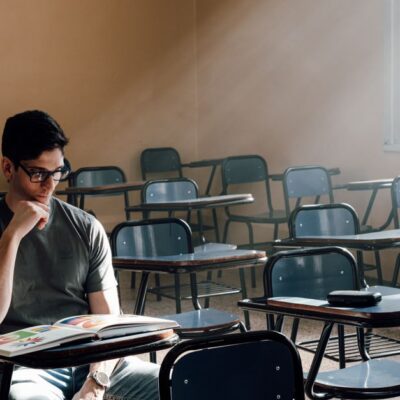 A person studies alone in an empty classroom with sunlight streaming through the window in Buenos Aires.