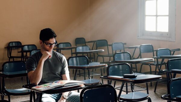 A person studies alone in an empty classroom with sunlight streaming through the window in Buenos Aires.