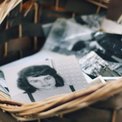 A collection of vintage black and white photos in a woven basket evokes nostalgia.