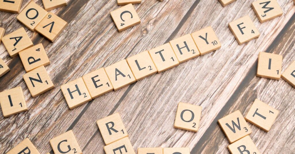 Wooden letter tiles arranged on a wooden surface spelling out 'healthy', symbolizing wellness.