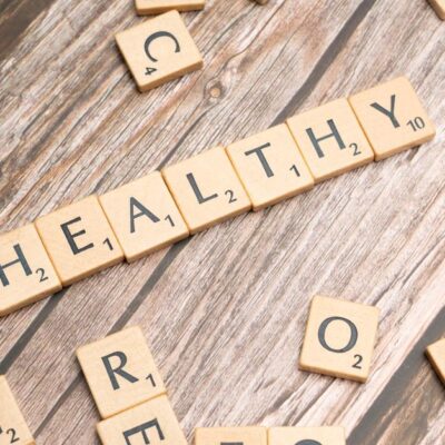 Wooden letter tiles arranged on a wooden surface spelling out 'healthy', symbolizing wellness.
