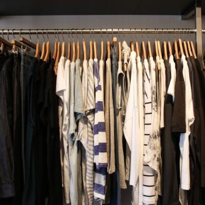 Diverse range of fashionable clothes on wooden hangers in a boutique setting.