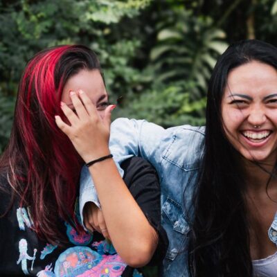 Two young women share a joyful moment outdoors, showcasing friendship and happiness.