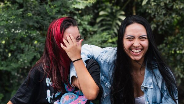 Two young women share a joyful moment outdoors, showcasing friendship and happiness.