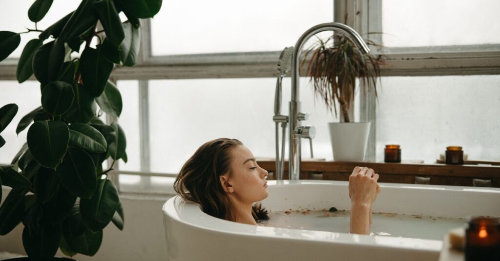 A woman peacefully soaking in a bathtub surrounded by plants and candles, embracing tranquility.