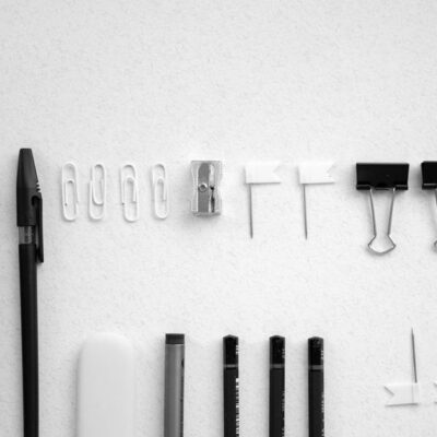 Neatly arranged office supplies including scissors, pens, and clips on a plain white background.