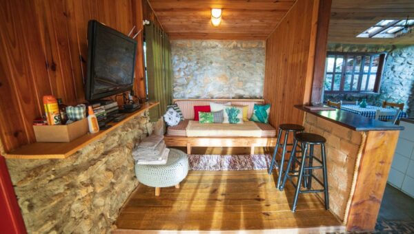 Interior of rustic house with counter placed near sofa with cushions and TV hanging on wooden wall near various supplies
