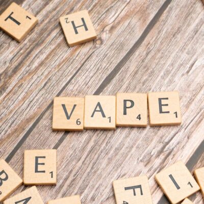 Wooden scrabble tiles with the word 'vape' on a textured wooden surface.