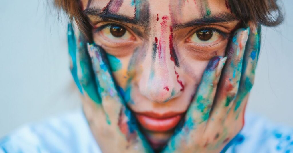 Como Transformar a Ansiedade em Criatividade Positiva 2 Close-up portrait of a young girl with a painted face and hands, showcasing creativity.