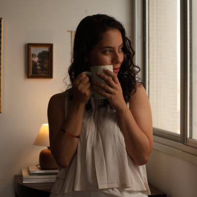 Young woman gazing out window with coffee, enjoying morning indoors.